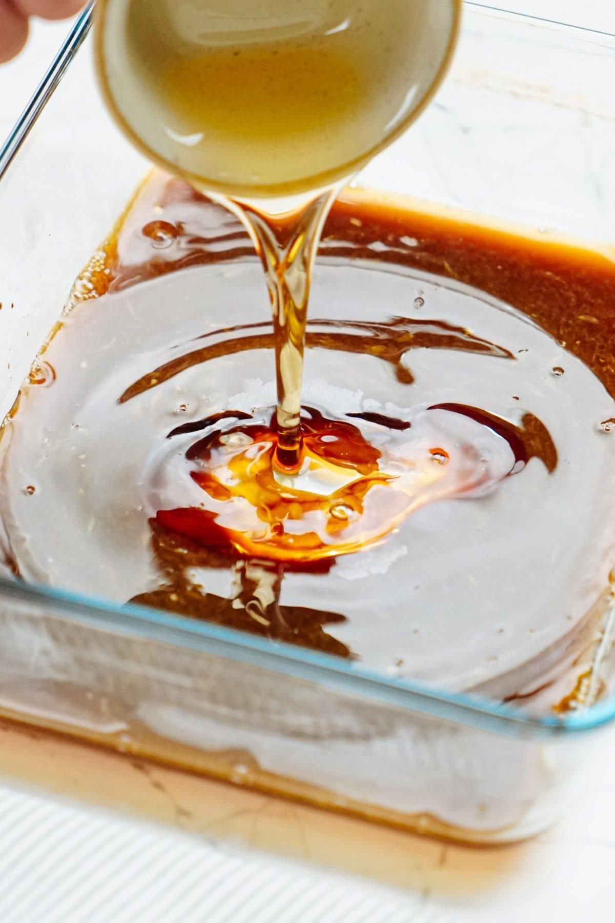 A person is pouring syrup into a baking dish