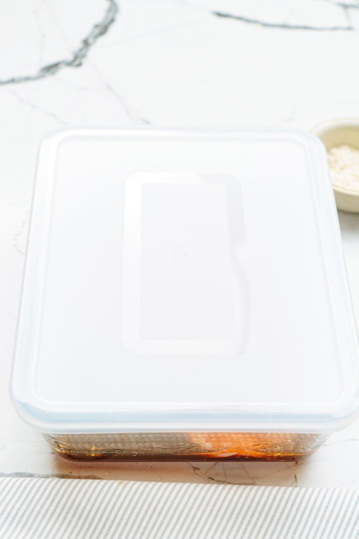 A plastic container with a lid placed on the marble table.