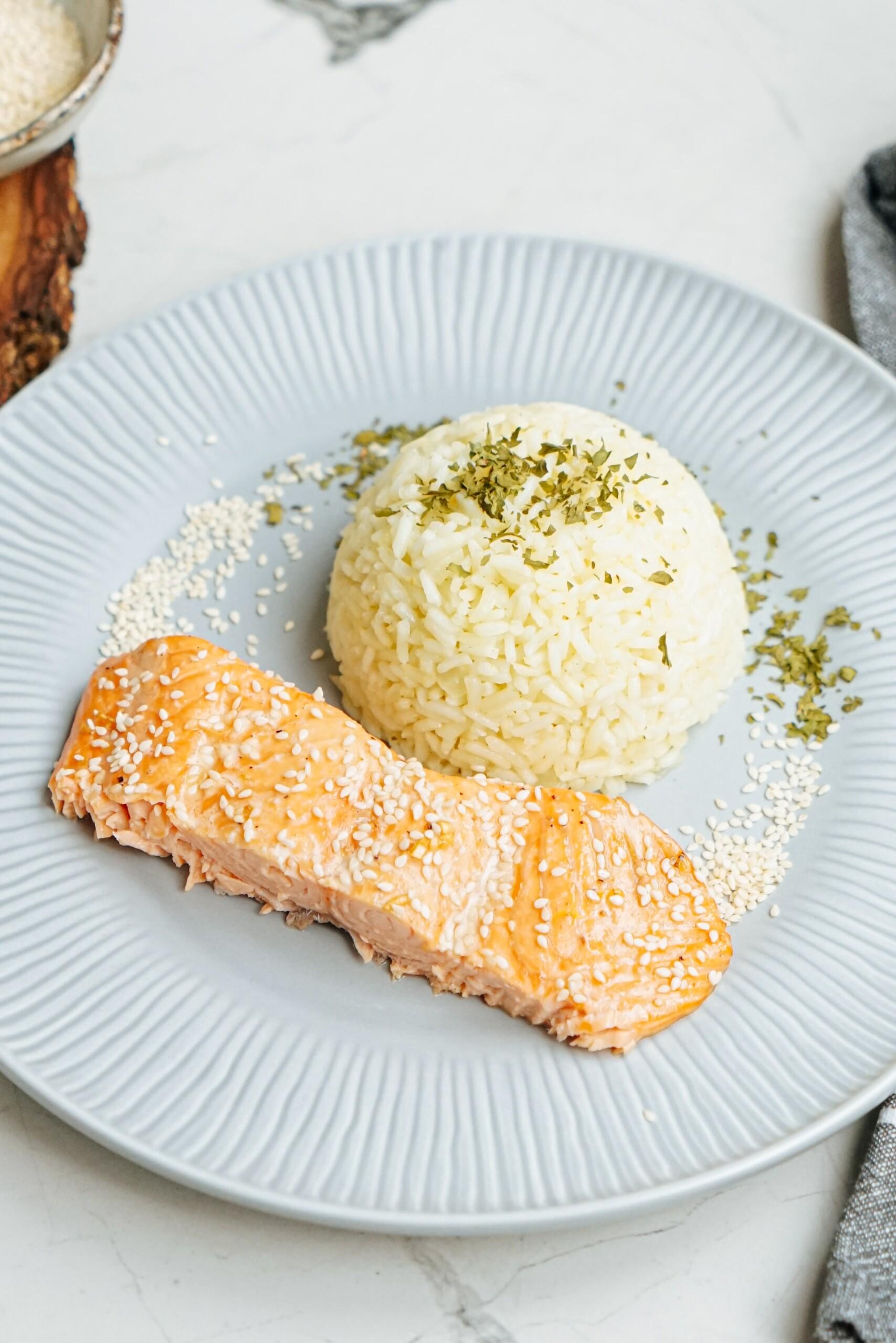 Salmon on a plate topped with sesame seeds.