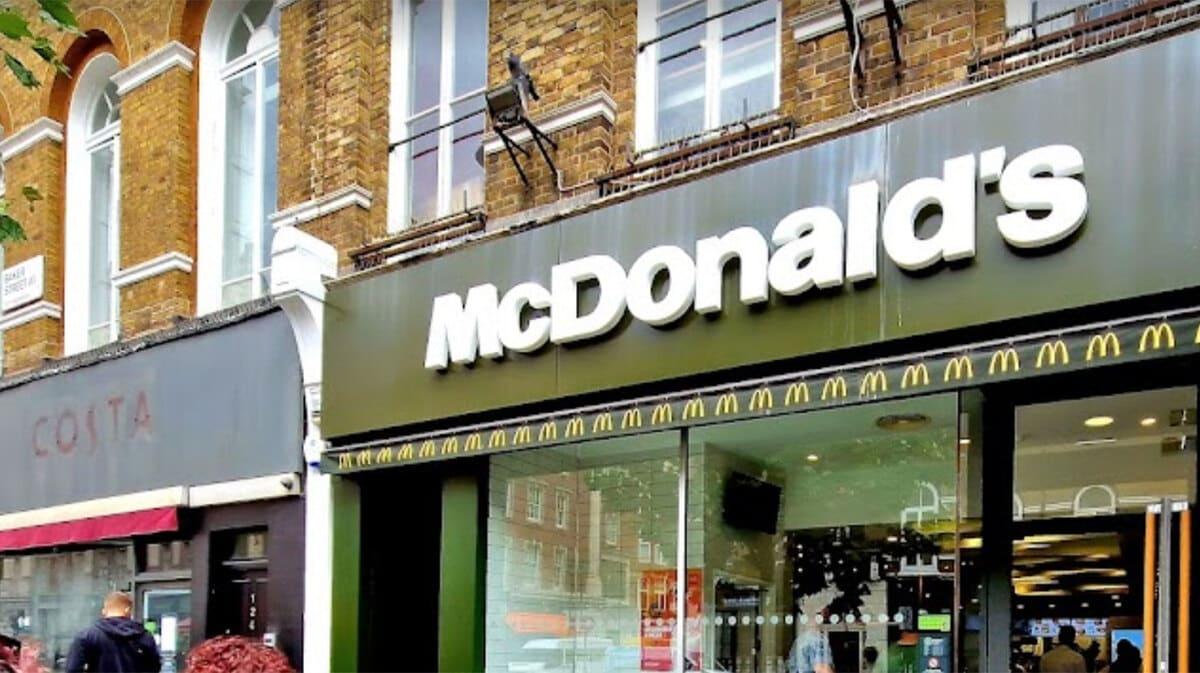 A mcdonald's store with people walking in front of it.