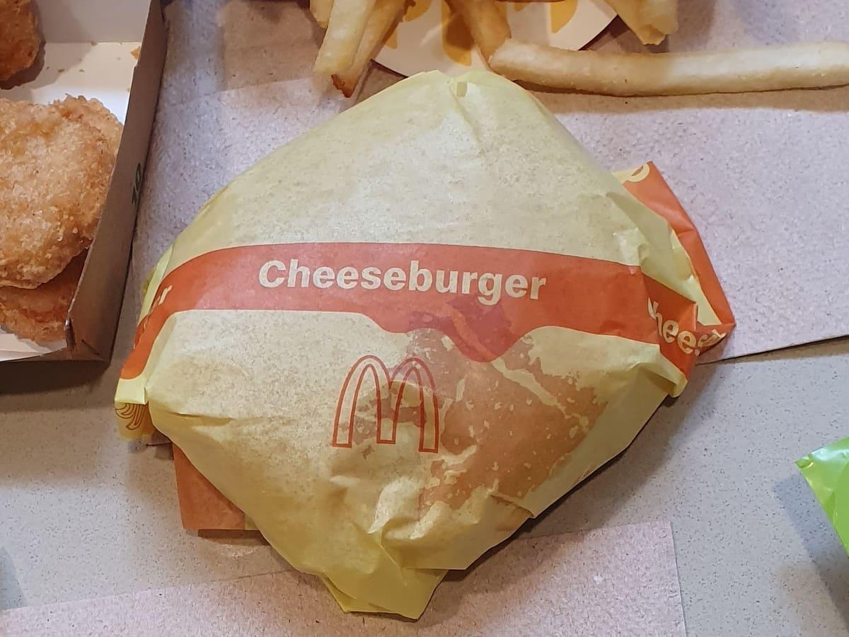 Mcdonald's cheeseburger with fries on a table.