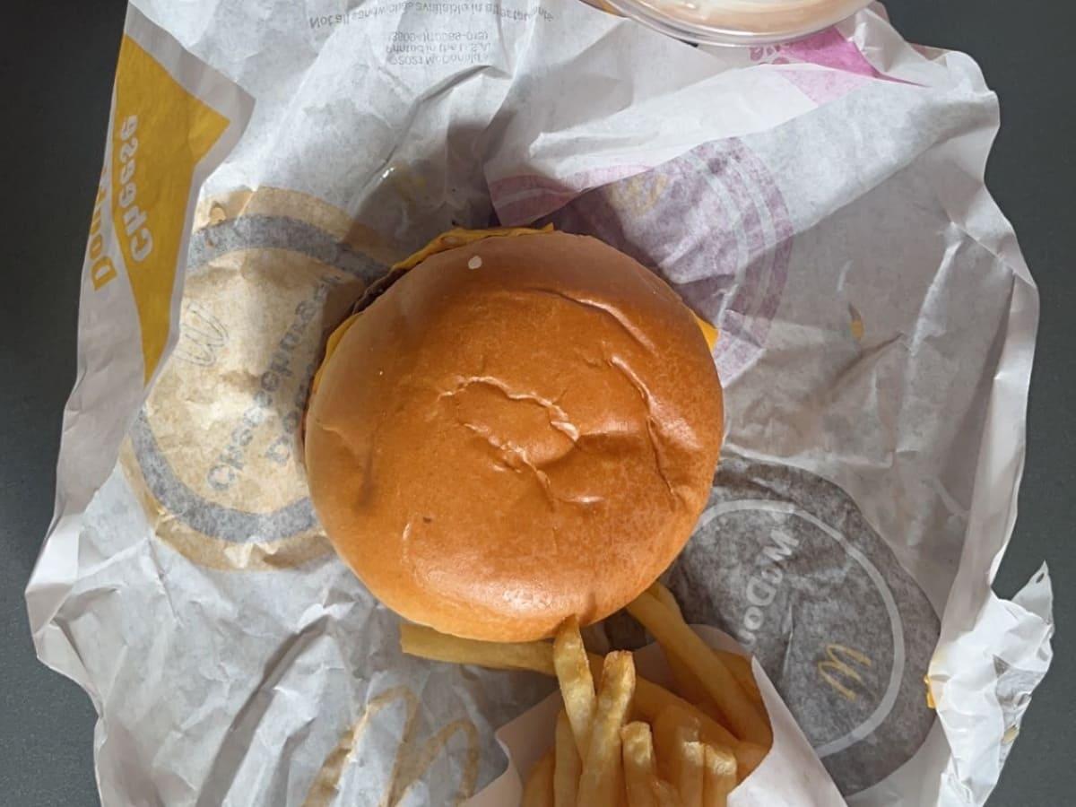 Mcdonald's cheeseburger with fries and a drink.