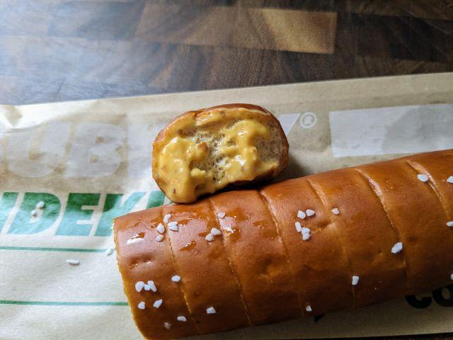 A piece of Subway's Footlong Pretzel dipped in honey mustard.