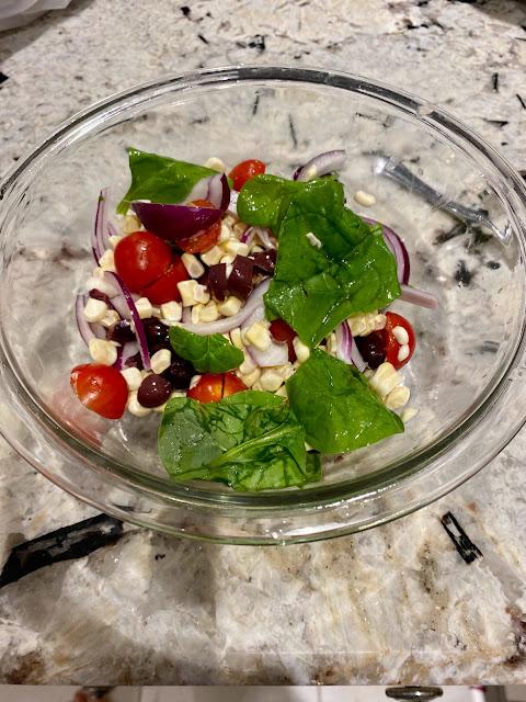 bowl of salad with corn kernels, tomatoes, olives,