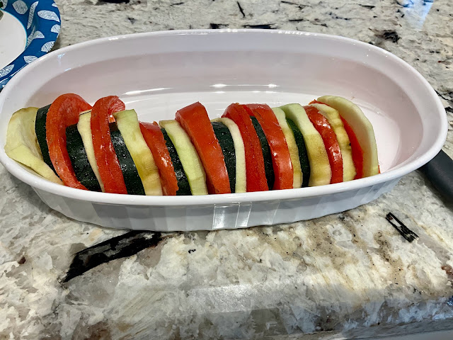 slices of tomato, zucchini, and eggplant alternately layered in a casserole