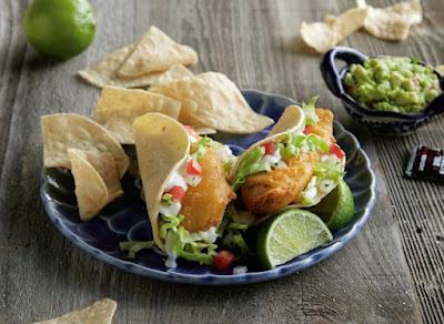 Del Taco's Beer Battered Crispy Fish Tacos made with Stone Buenaveza Salt & Lime Lager on a plate with chips and guacamole.