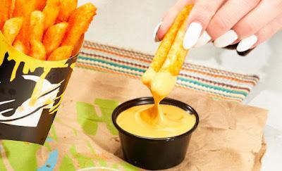 Taco Bell Nacho Fries being dipped in new Vegan Nacho Sauce.