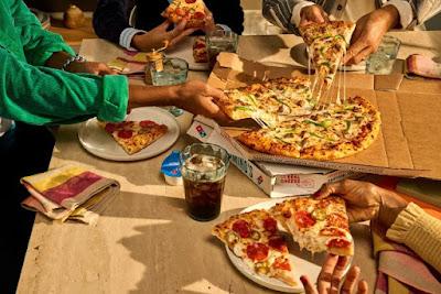 Domino's large 2-topping pizza being shared among a group of people.