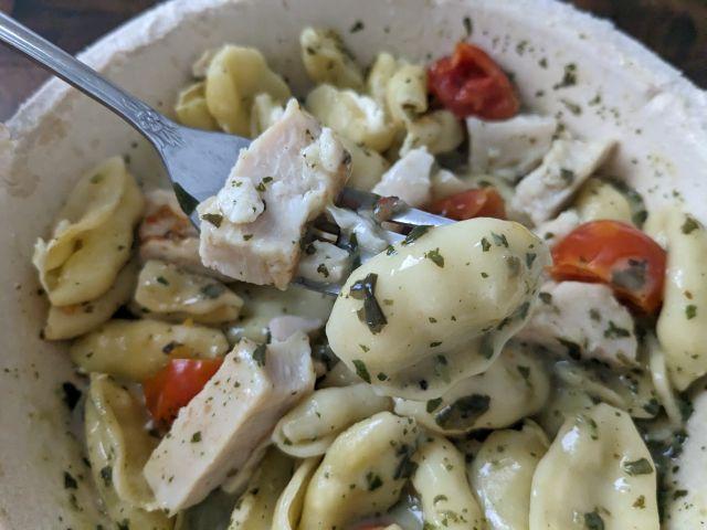 Marie Callender's Grilled Chicken Pesto Pasta Bowl close-up of fork with chicken and pasta.