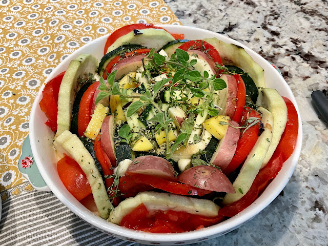 a small casserole dish with layers of tomato, zucchini, and eggplant