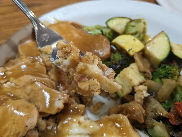 A fork of Denny's turkey, gravy, and stuffing.