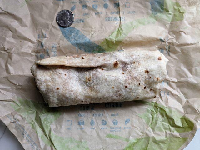 Taco Bell's Chicken Enchilada Burrito next to a quarter.