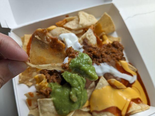 Close up of a chip with beef and guacamole from Taco Bell Loaded Beef Nachos.