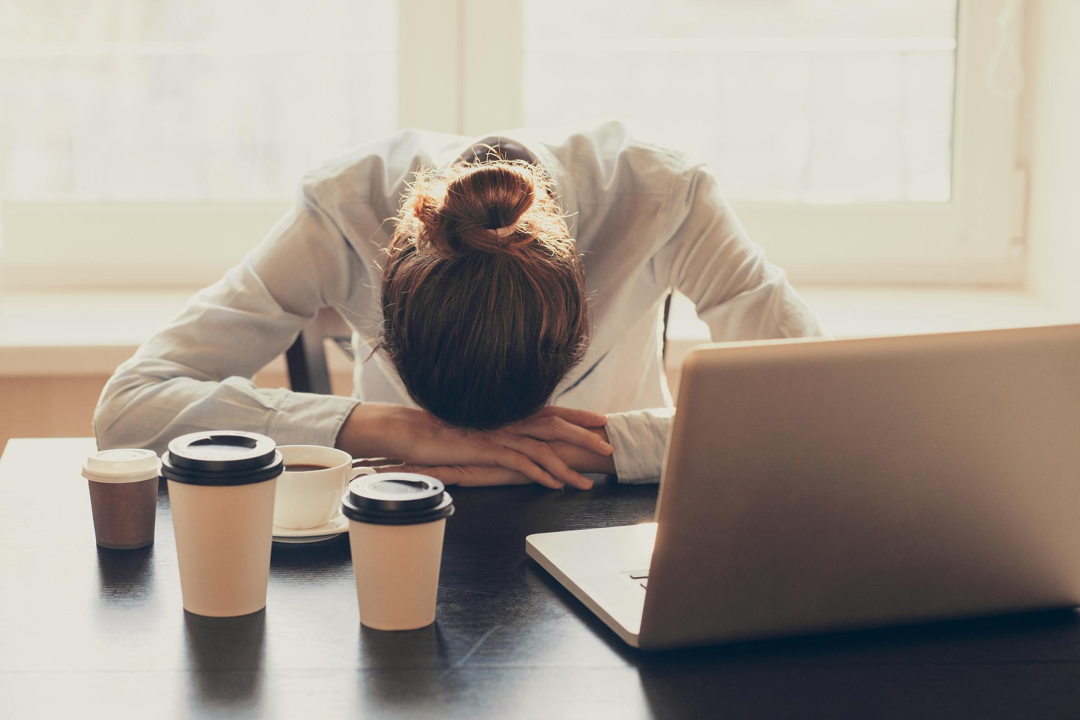 Woman Tired with Several Cups of Coffee in Front of Her | Catch Up on Sleep