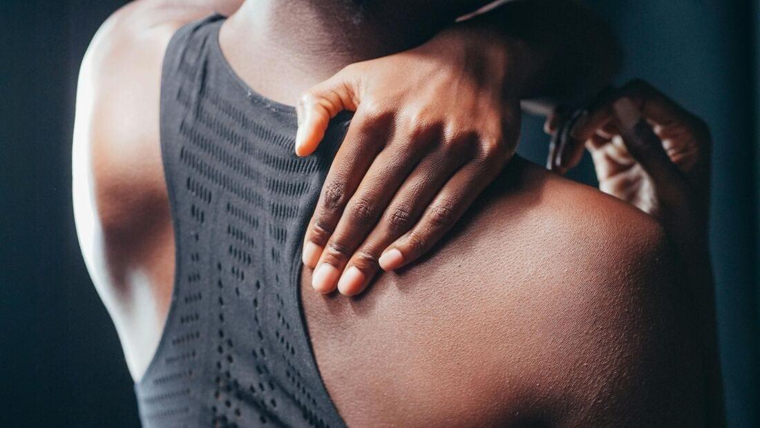A young black woman rubbing her shoulder as if in pain, likely from bodily inflammation.