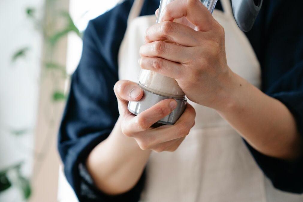 A female is about to blend protein powder to make a shake. The image shows her blender glass in her hands.