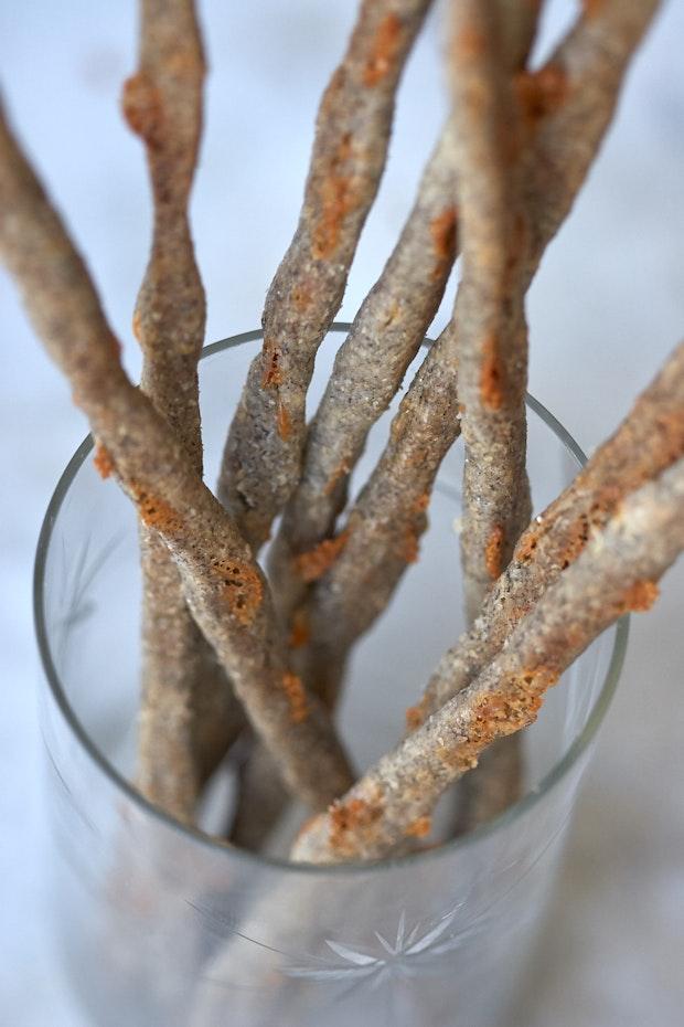 cheese straws standing upright in a glass