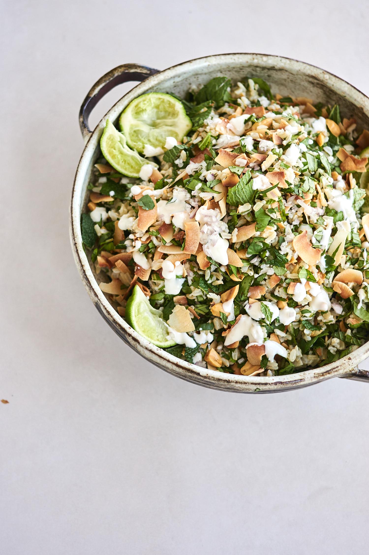 ceramic bowl filled with rice salad recipe topped with lots of herbs and topped with peanuts