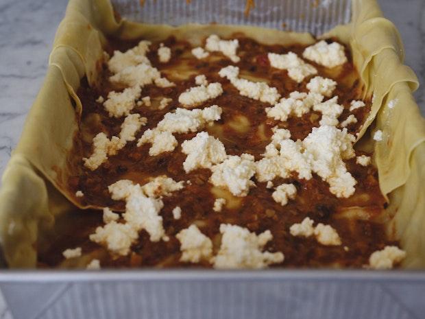 Mushroom Lasagna being layered in a Baking Pan with ragu, ricotta cheese and pasta noodles