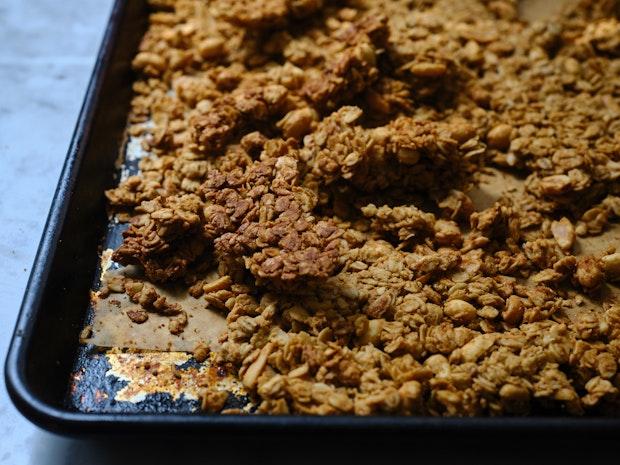 clumps of peanut butter granola on a rimmed baking sheet