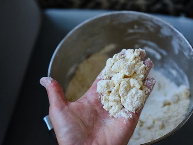 shards of butter coated in flour in baker's hand