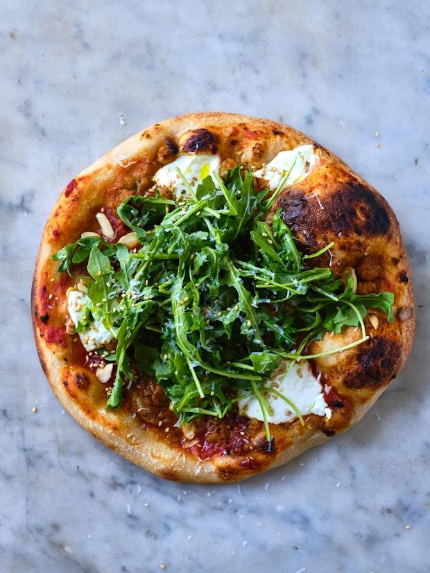 Pizza with red sauce and arugula as pizza toppings