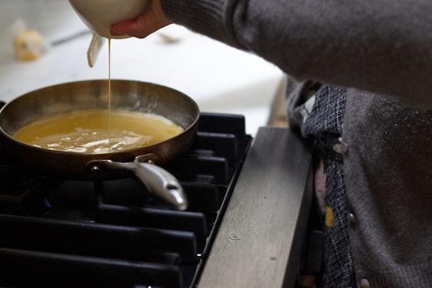 Pouring eggs into a buttered skillet to make scrambled eggs