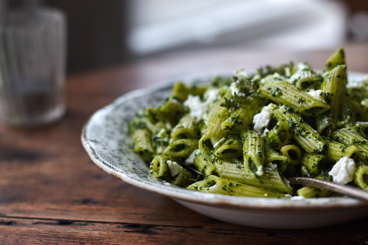 penne pasta made with winter greens like kale and goat cheese on a floral plate