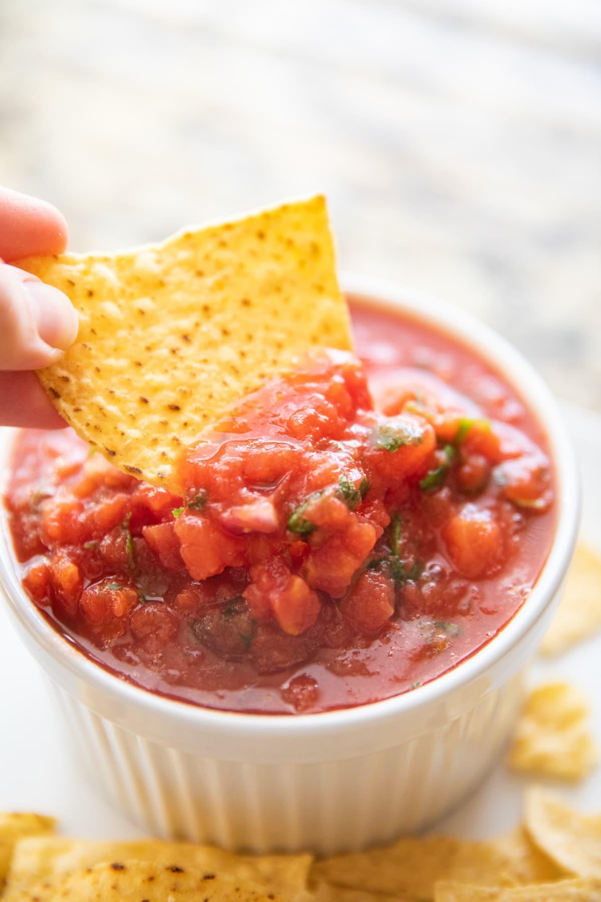 dipping tortilla chip into salsa