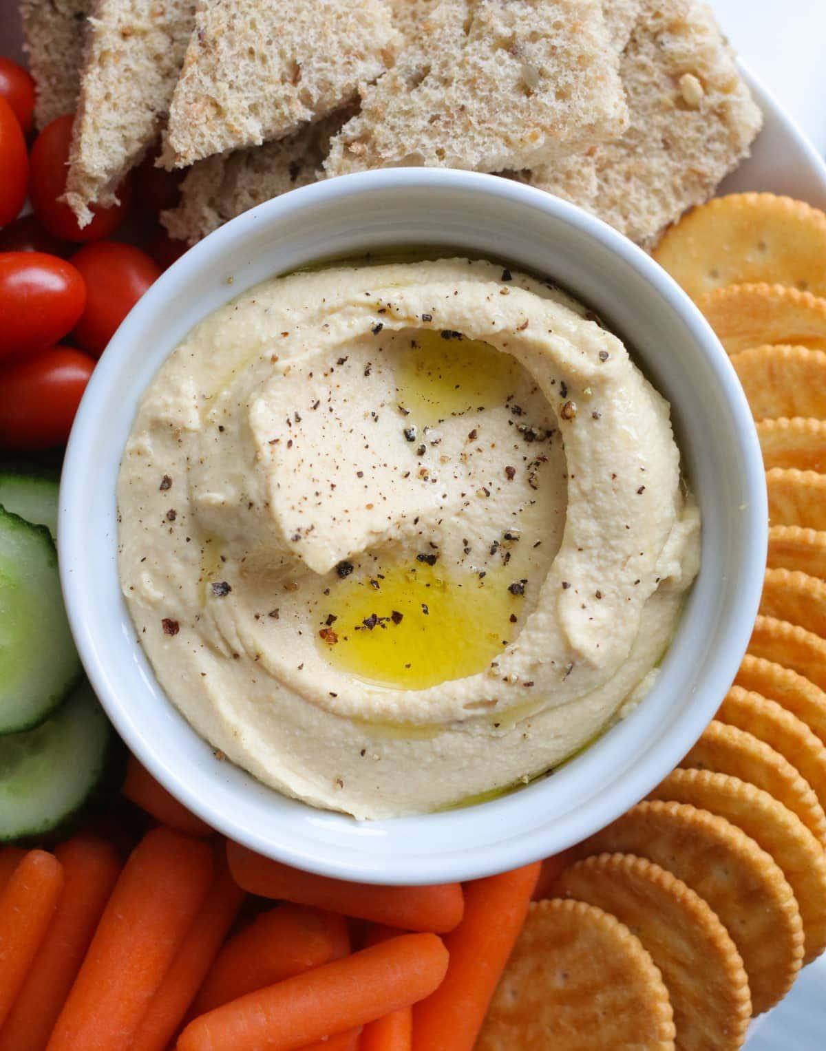 Hummus in a bowl with dipping options around it