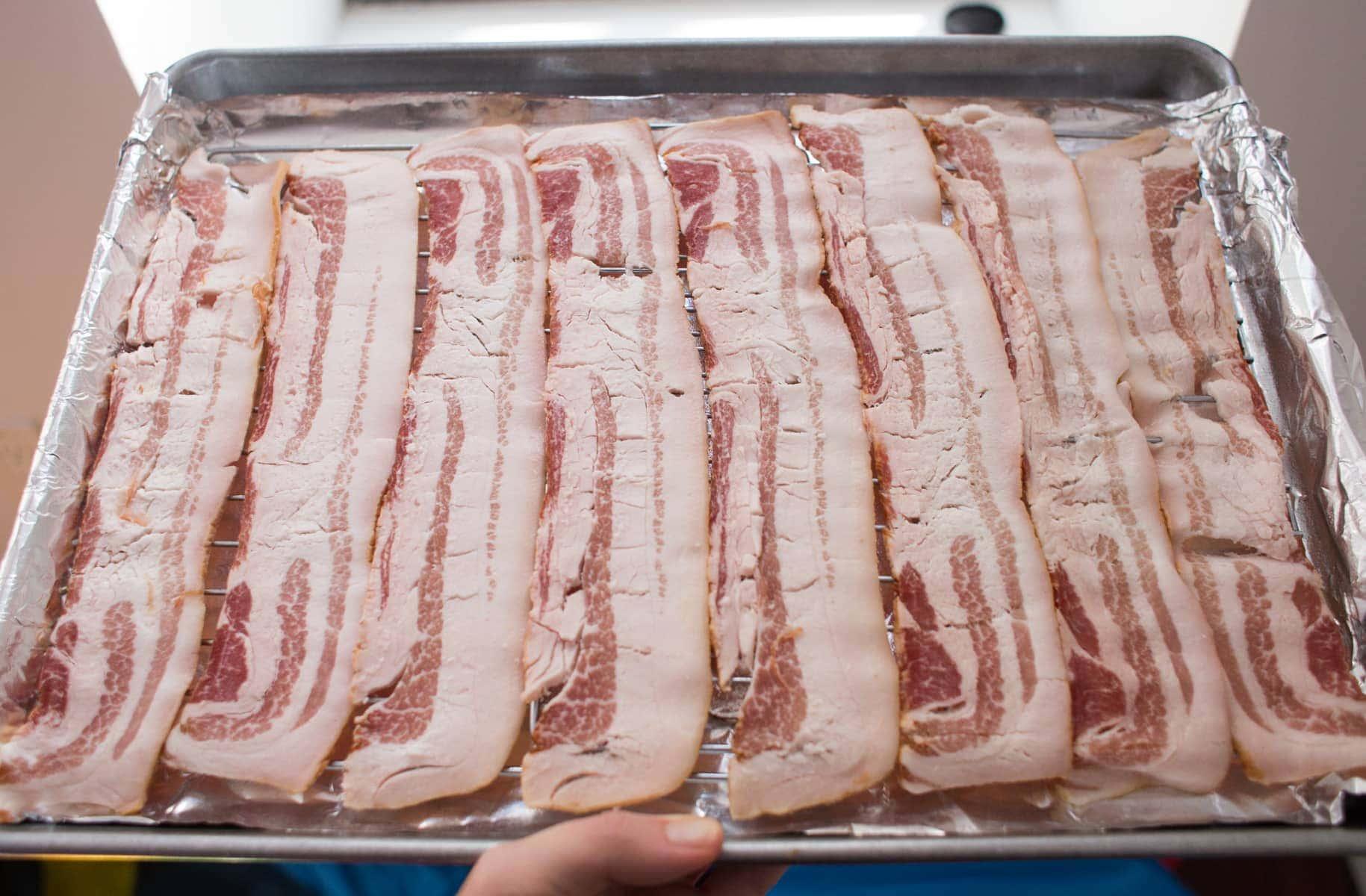 raw bacon on baking sheet with rack