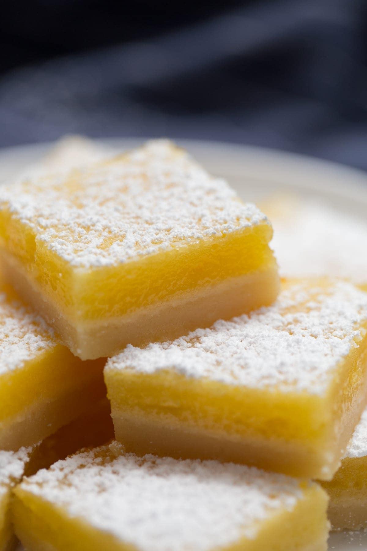 lemon bars stacked on top of each other on a white plate