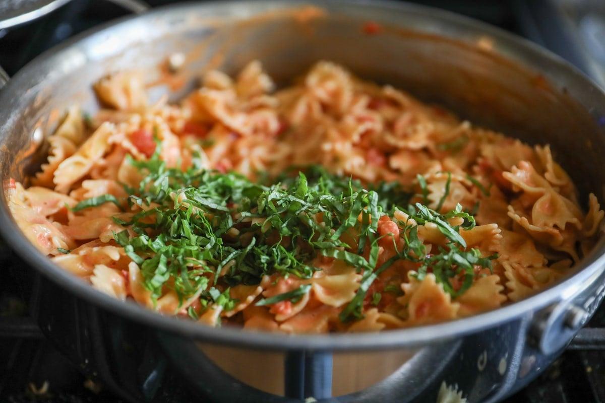 chopped fresh basil on top of bow tie pasta with sauce