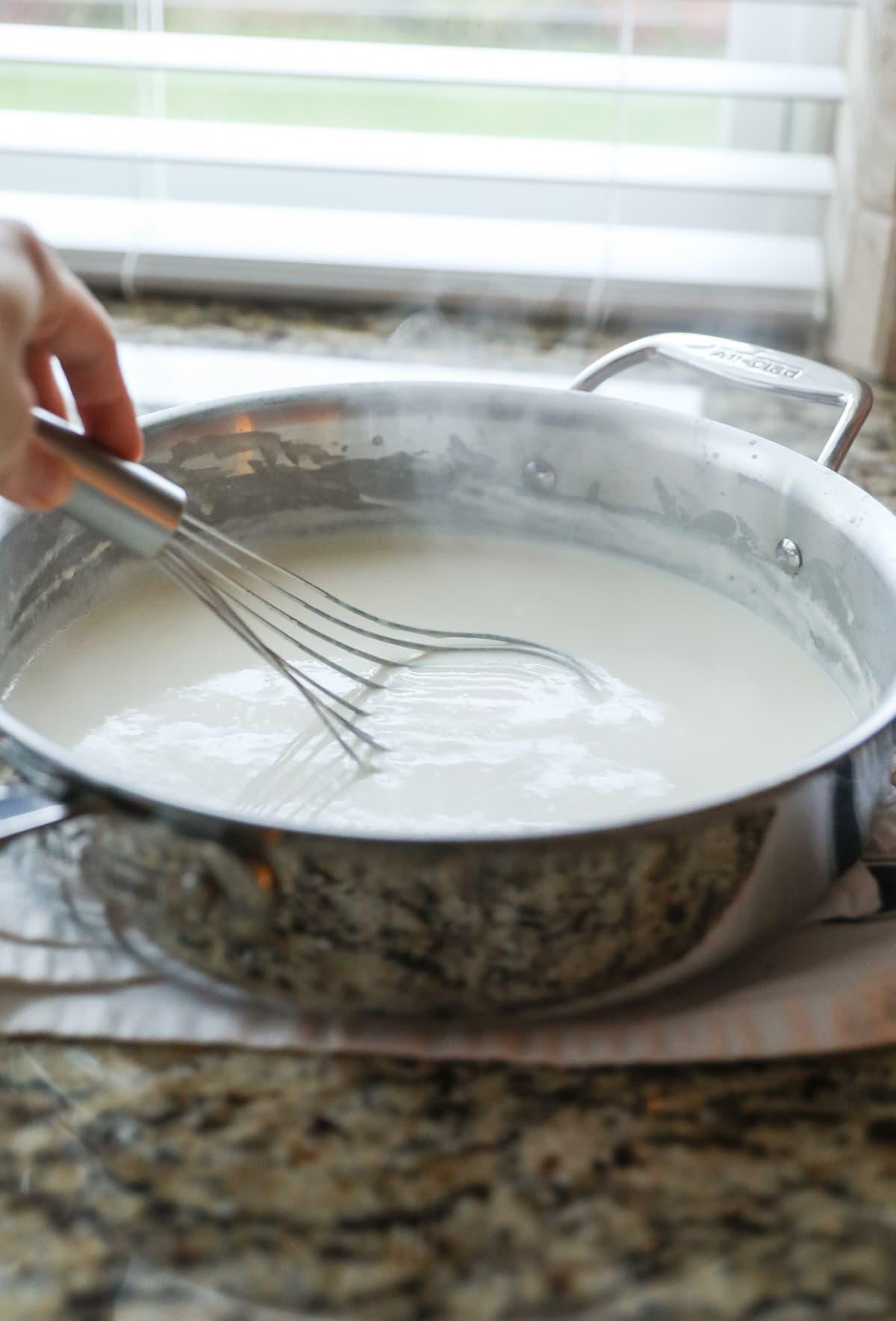 whisking healthy alfredo sauce in pan