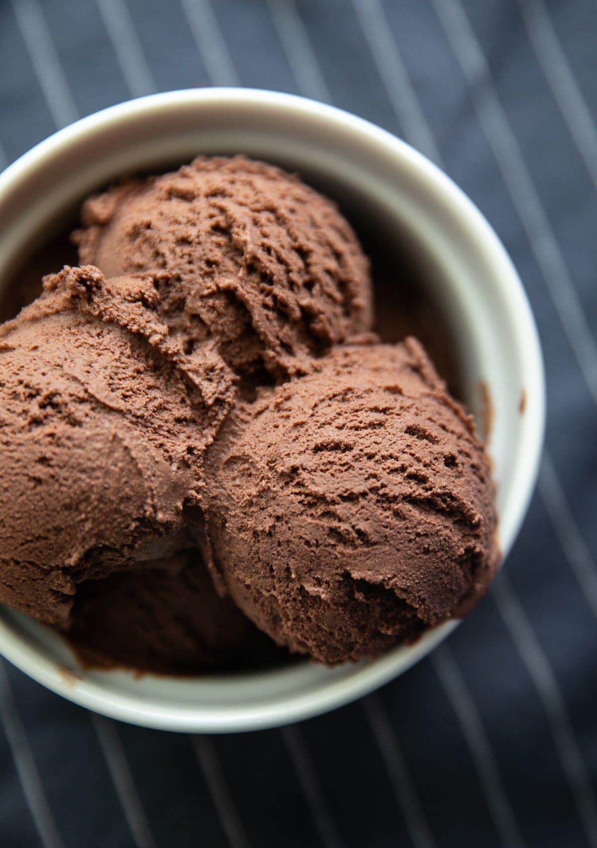 top down view of chocolate ice cream scoops in a white bowl