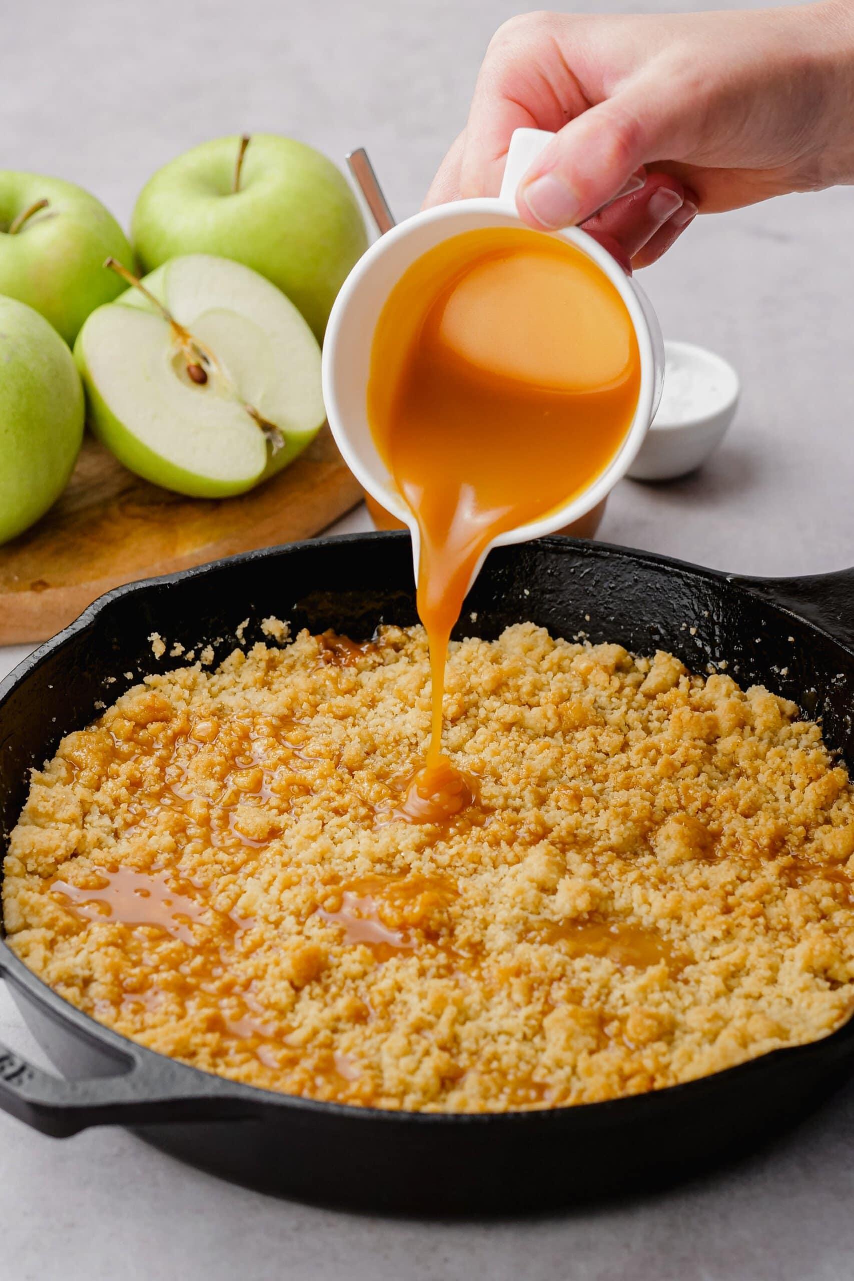 pouring more salted caramel sauce over crumble topping