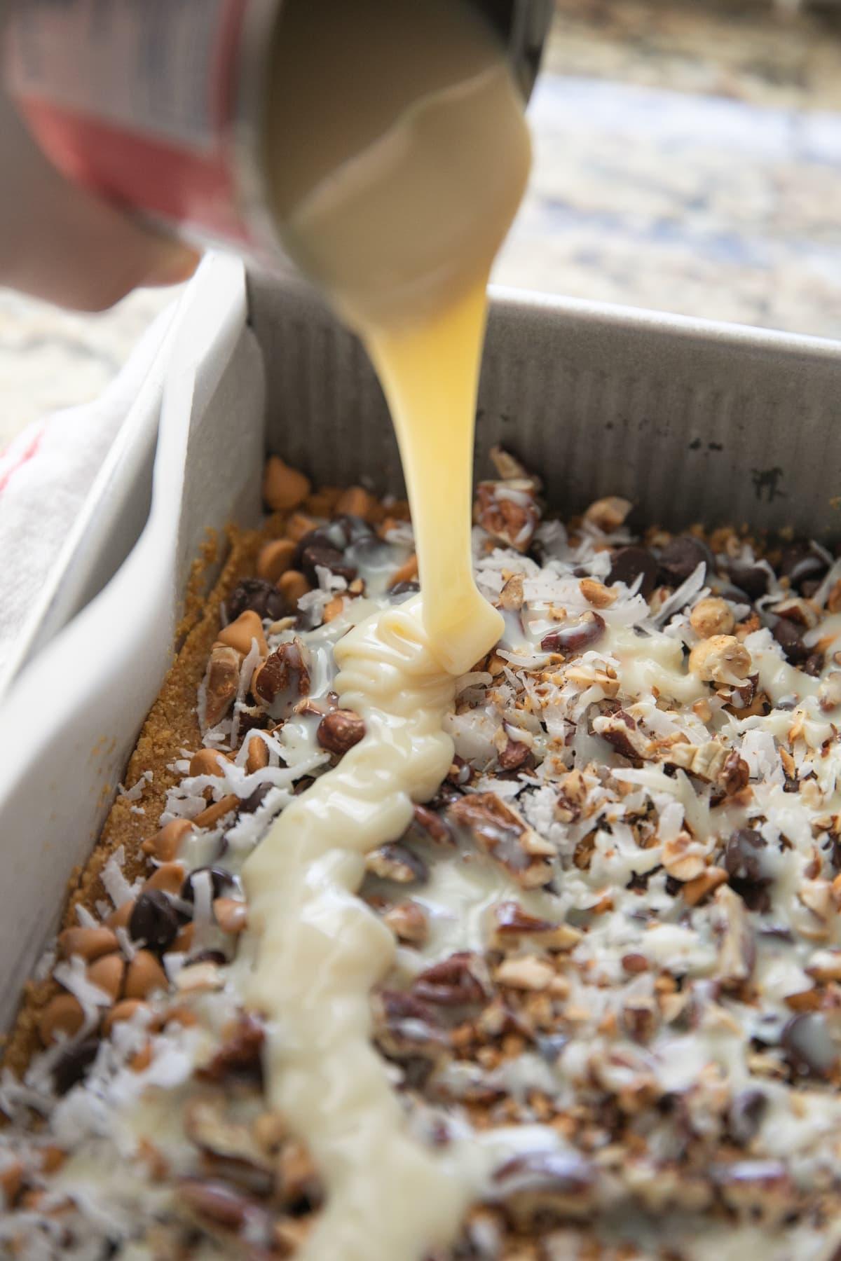 pouring sweetened condensed milk over unbaked bars