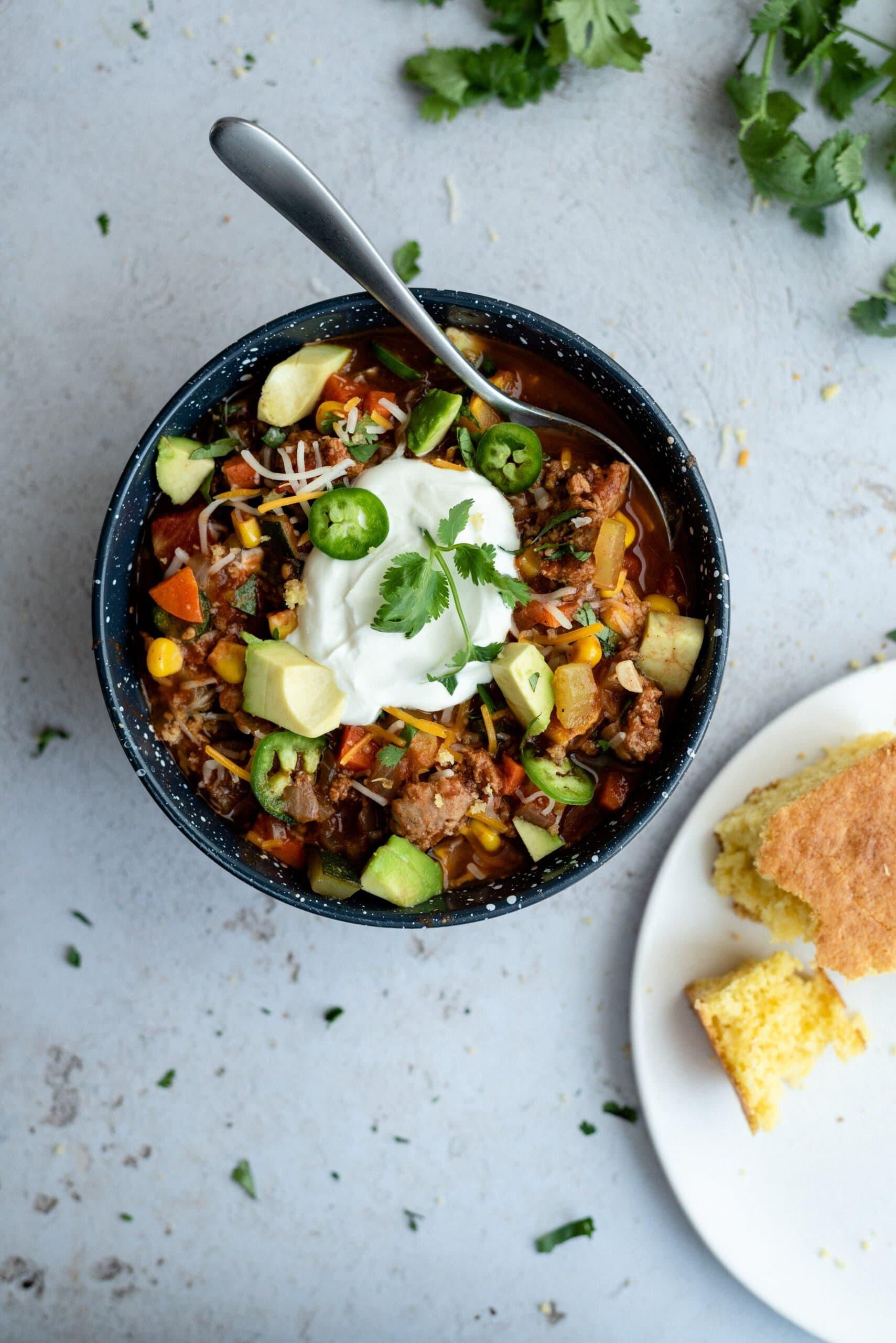 top down view of no bean chili in a bowl next to cornbread