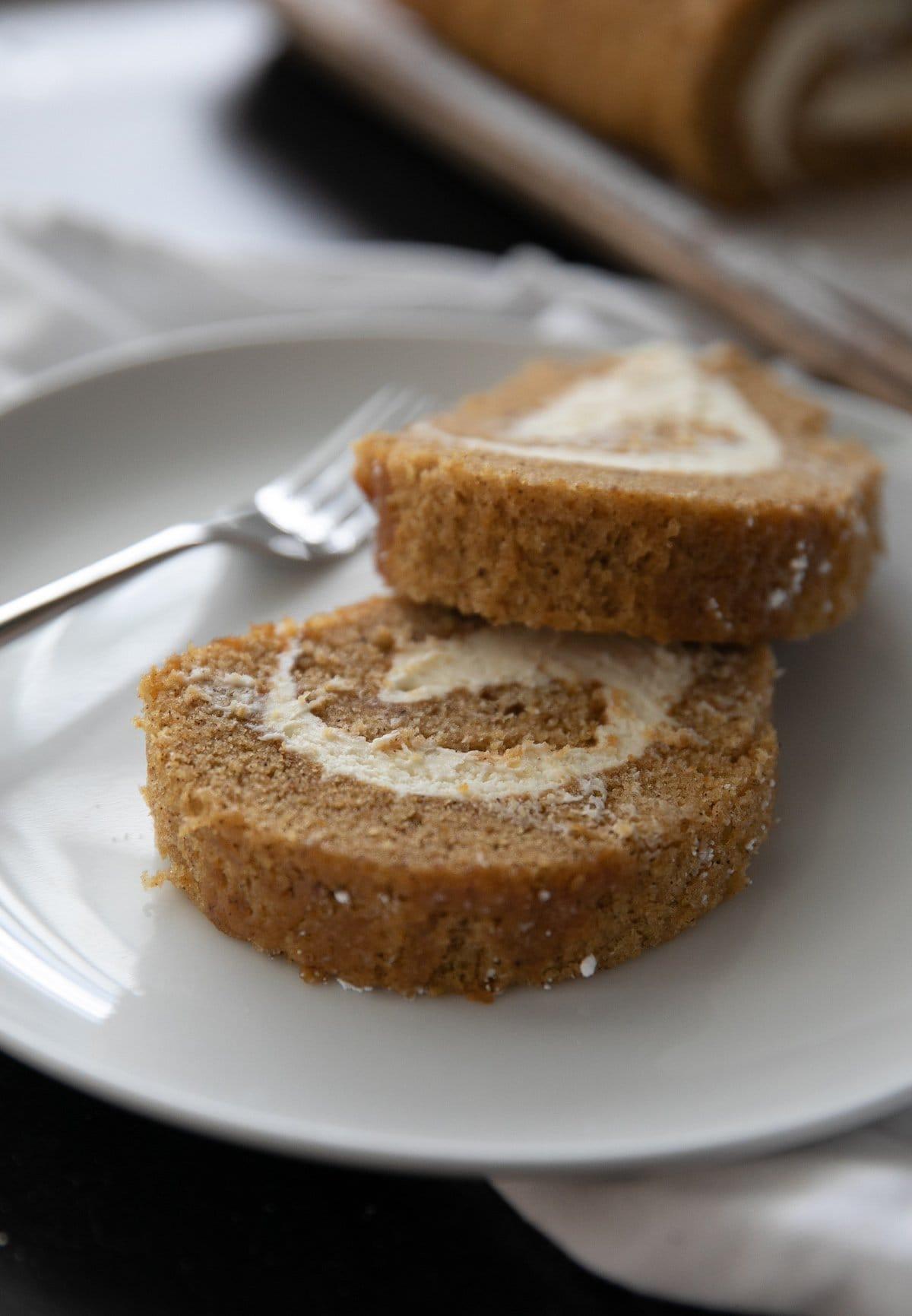 two slices of pumpkin roll cake on a white plate