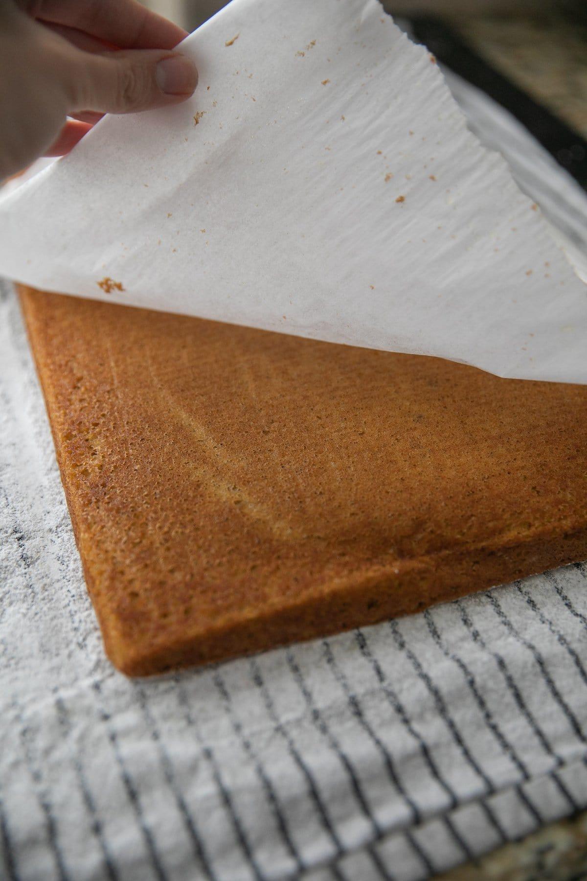 parchment paper being lifted off of pumpkin sponge cake