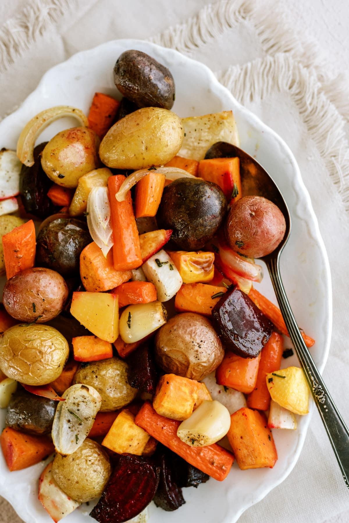 cooked roasted root vegetables on platter with spoon