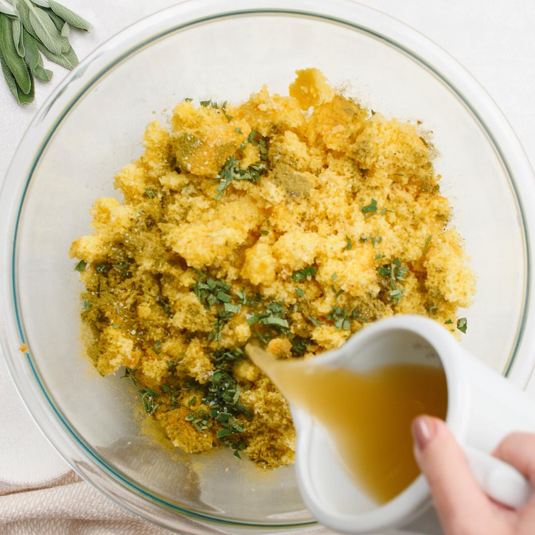 adding chicken stock to cornbread stuffing in pan