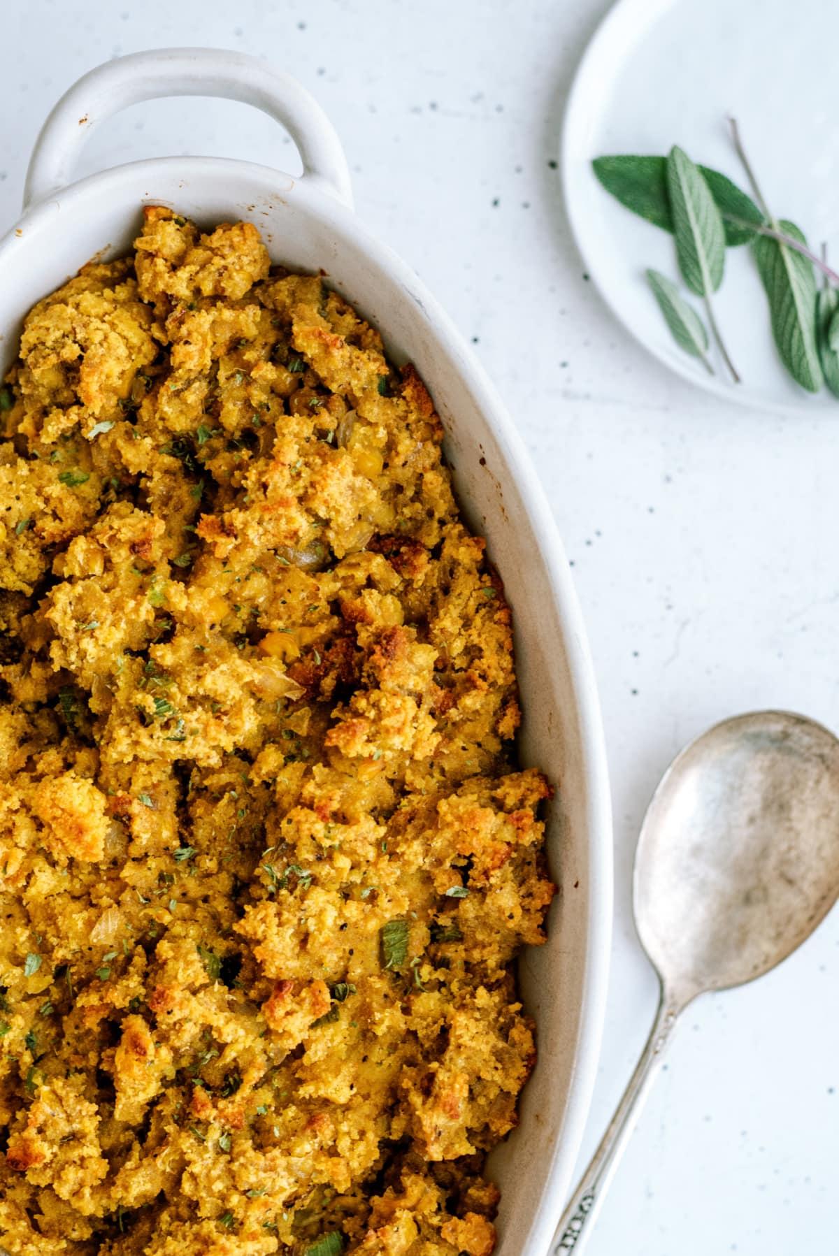 cornbread stuffing in dish with serving spoon next to it on table