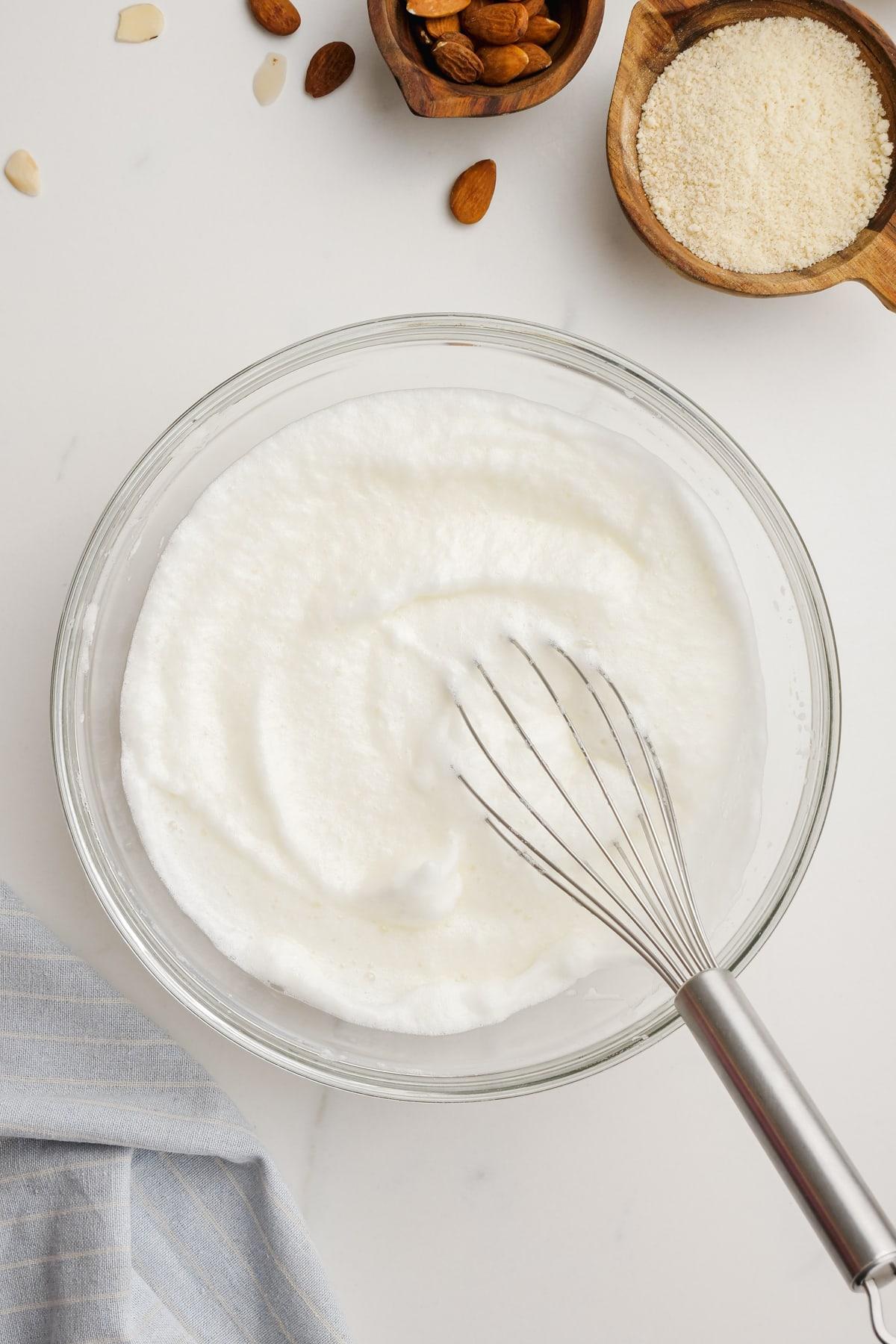 fluffy egg whites in bowl with whisk