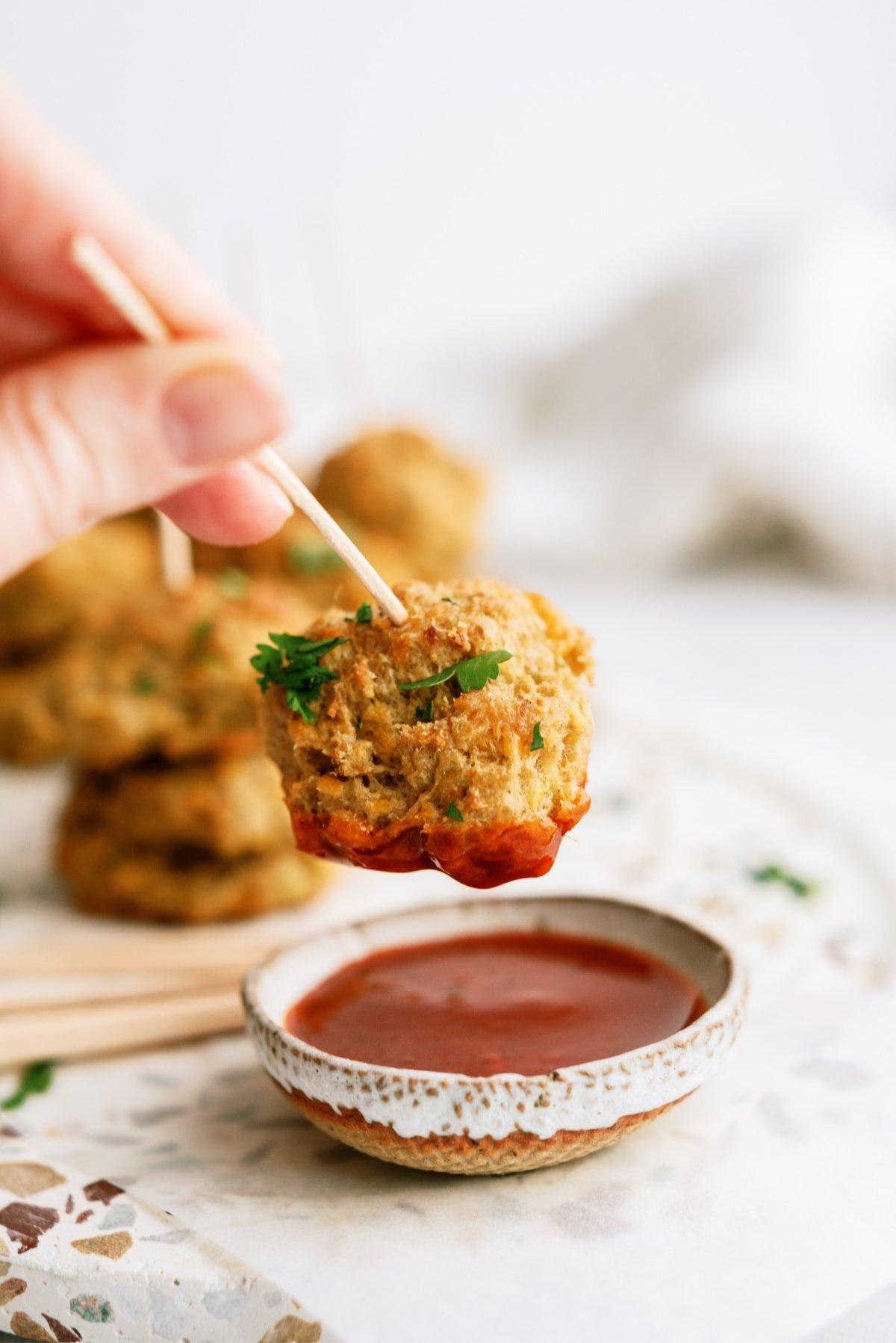 woman's hand dipping sausage bowl in sauce