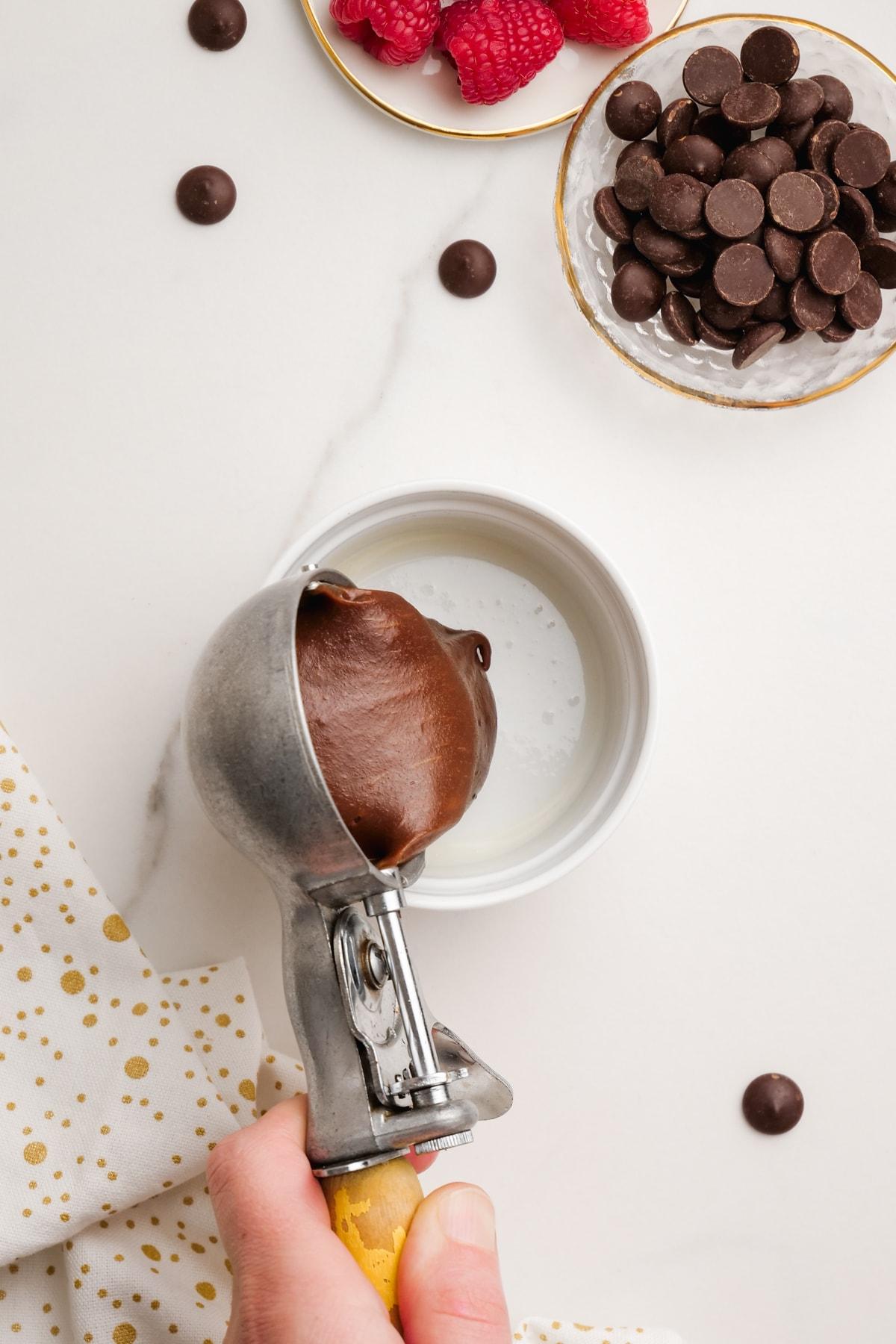 woman's hand scooping molten lava cake ingredients into ramekan