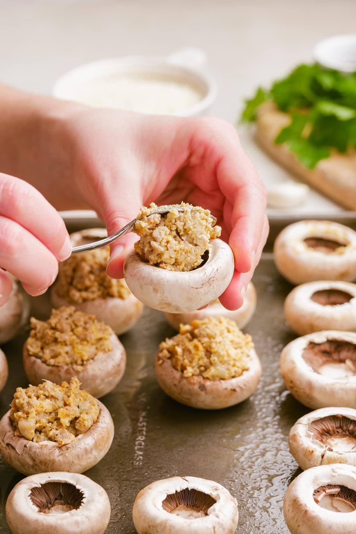 sausage stuffed mushrooms 9 woman placing filling into mushroom with spoon