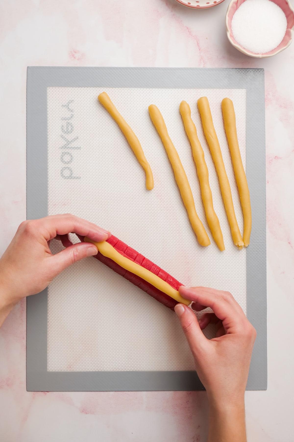 woman's hands sticking dough snakes onto red heart stacks