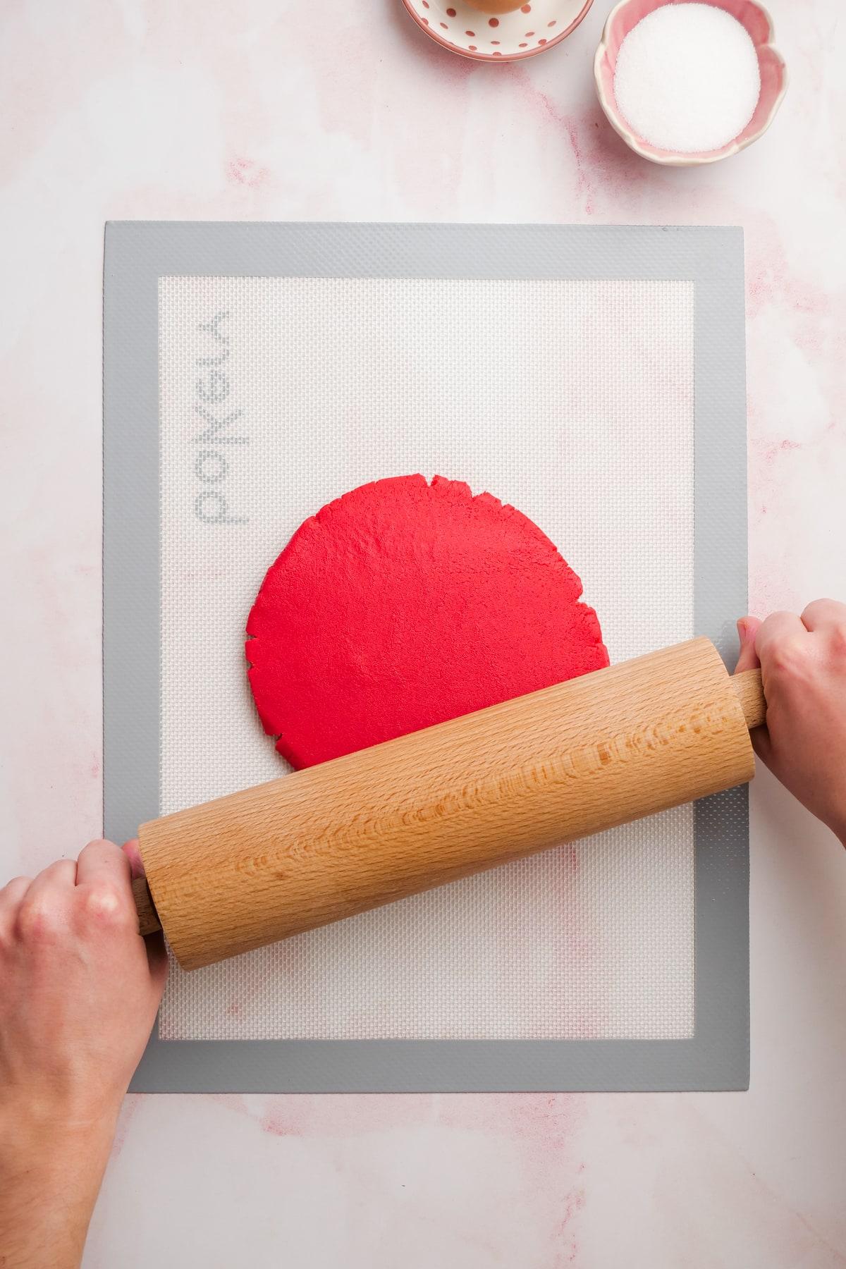 rolling out red cookie dough with rolling pin