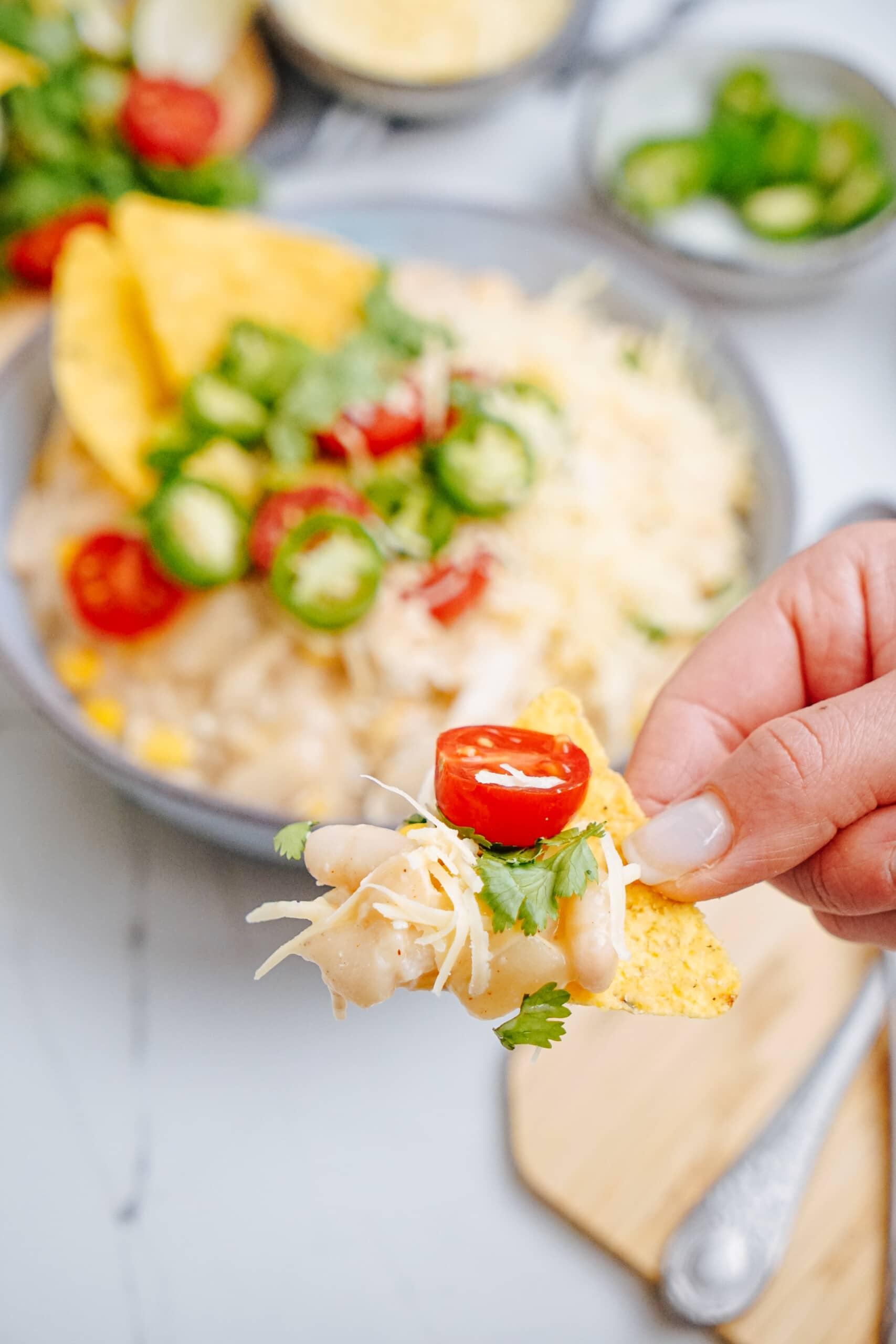 woman's hand holding chip with white chicken chili